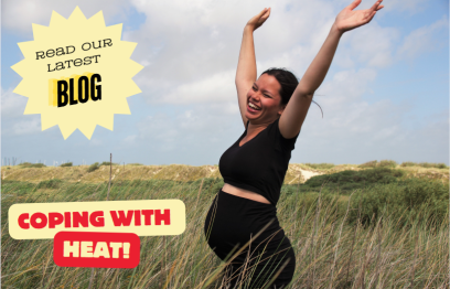 A pregnant woman smiling and waving her arms in the air. She is standing among sand dunes.
