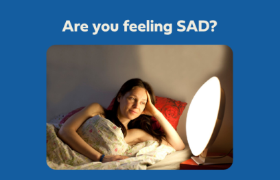 A woman lies in bed with a light therapy lamp. (Getty Images)