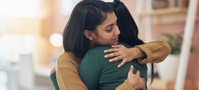 2 women embraced in a supportive hug