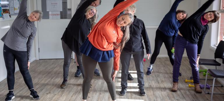 Image of our trainer Jen doing a side stretch with strength class participants